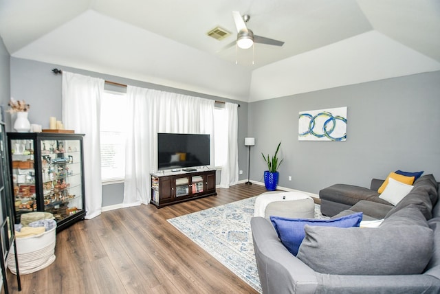 living area with a healthy amount of sunlight, visible vents, wood finished floors, and lofted ceiling