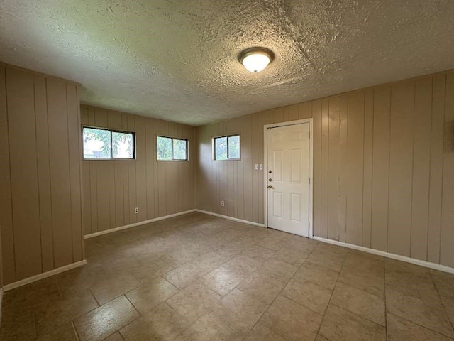 spare room featuring a textured ceiling and wood walls