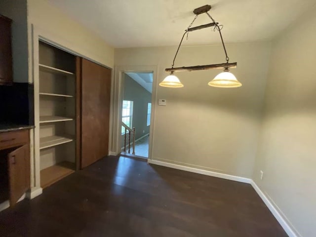 unfurnished dining area with dark wood-type flooring