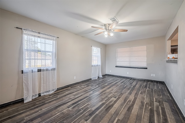 spare room with a healthy amount of sunlight, ceiling fan, and dark hardwood / wood-style flooring