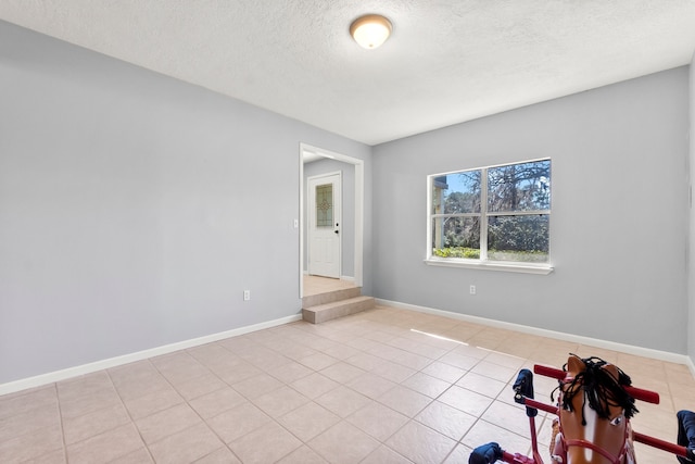 unfurnished room featuring baseboards, a textured ceiling, and light tile patterned flooring