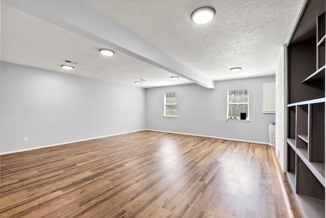 interior space featuring visible vents, a textured ceiling, baseboards, and wood finished floors