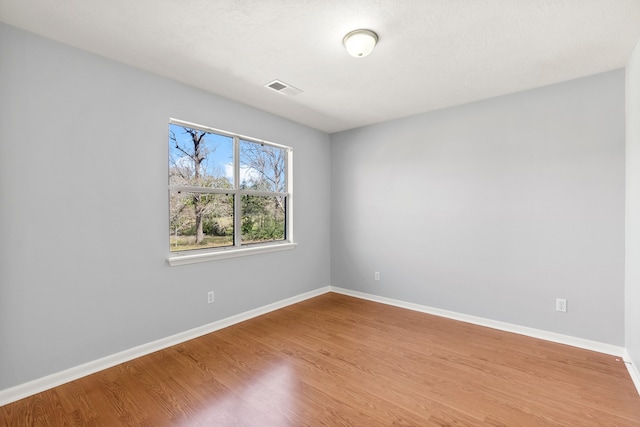 unfurnished room with baseboards, visible vents, and wood finished floors