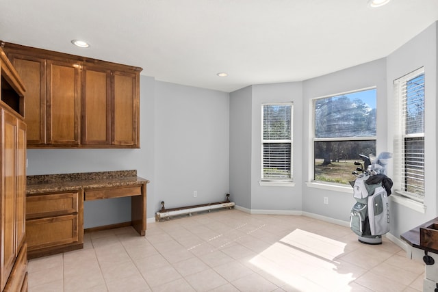 interior space featuring light tile patterned floors, baseboards, and brown cabinets