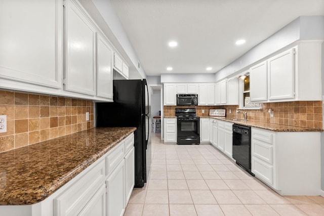 kitchen featuring dark stone counters, white cabinets, a sink, and black appliances