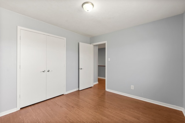 unfurnished bedroom with light wood-style floors, a closet, and baseboards