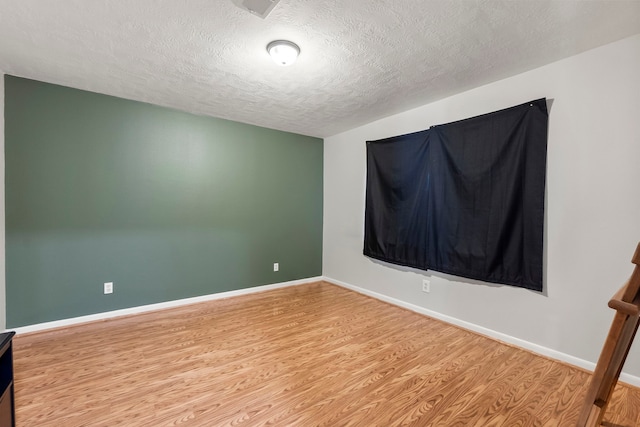 unfurnished room with baseboards, a textured ceiling, and light wood-style floors