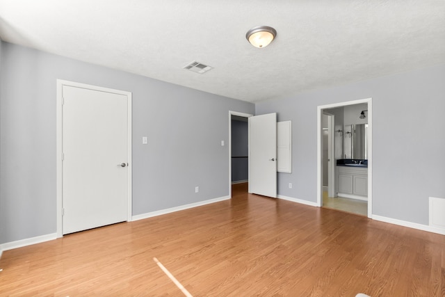 empty room featuring baseboards, a textured ceiling, visible vents, and wood finished floors