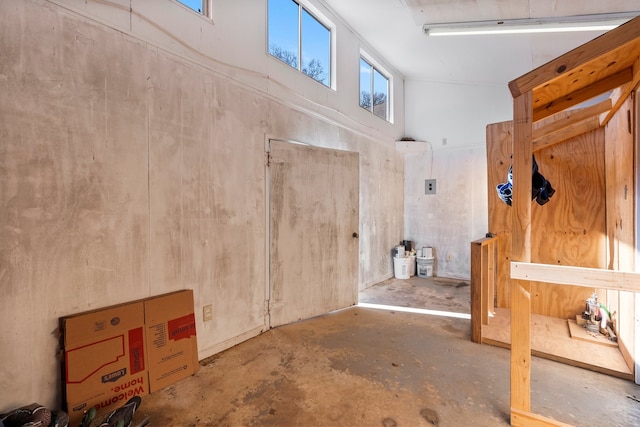 miscellaneous room with concrete flooring and high vaulted ceiling