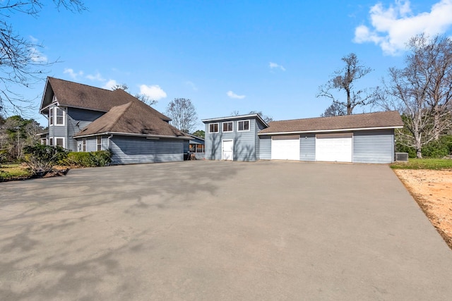 view of front of property featuring a garage, an outdoor structure, and central AC