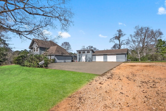 view of front of home featuring a front yard, a detached garage, and an outdoor structure