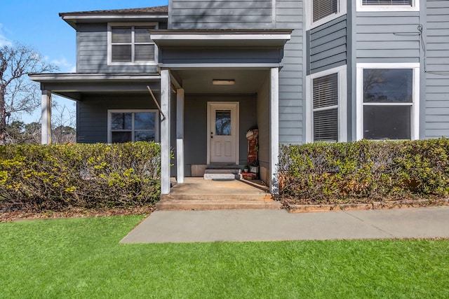 view of exterior entry featuring a lawn