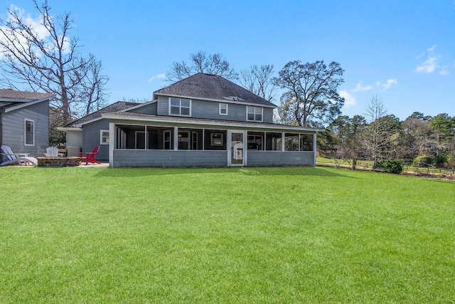 back of house with a lawn, a sunroom, and an outdoor fire pit