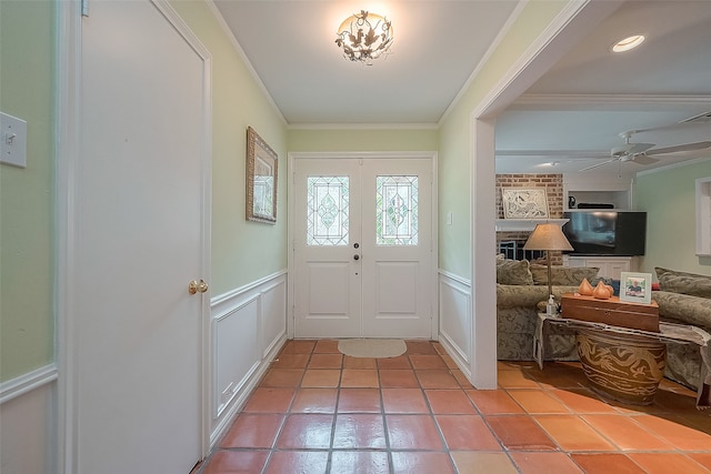 tiled entryway featuring brick wall, ceiling fan, and ornamental molding