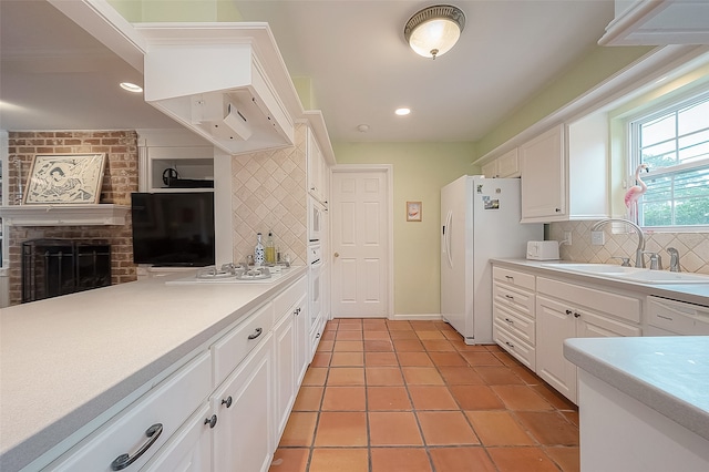 kitchen with sink, light tile patterned floors, a fireplace, tasteful backsplash, and white cabinetry