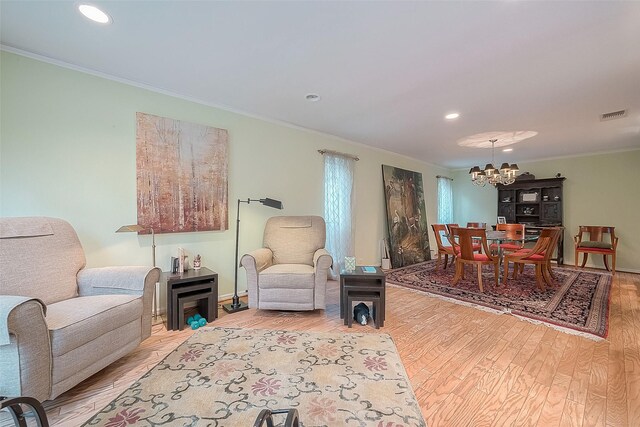 living room featuring a notable chandelier, crown molding, and light wood-type flooring