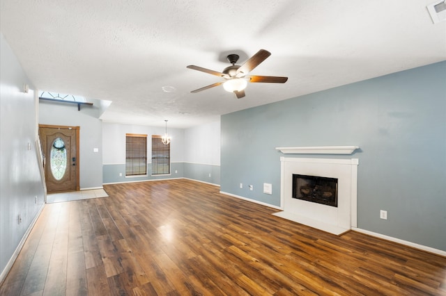 unfurnished living room featuring ceiling fan with notable chandelier, hardwood / wood-style floors, and a textured ceiling