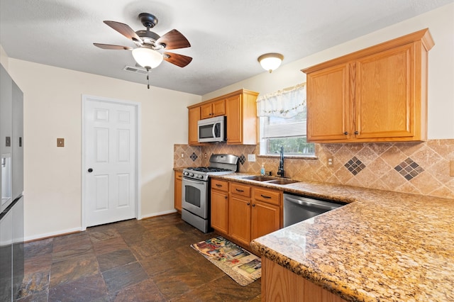 kitchen with ceiling fan, decorative backsplash, appliances with stainless steel finishes, light stone counters, and sink