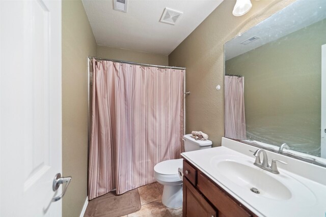 bathroom with tile patterned floors, vanity, walk in shower, and toilet