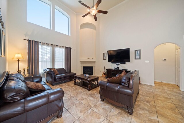 living room featuring a high ceiling, ceiling fan, light tile patterned flooring, and crown molding