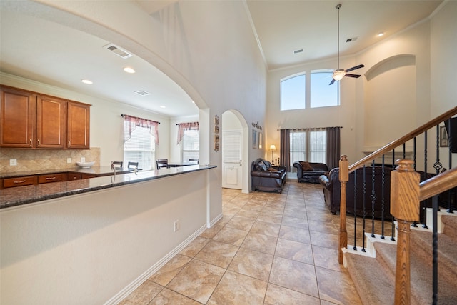 kitchen with a high ceiling, light tile patterned floors, tasteful backsplash, and a healthy amount of sunlight