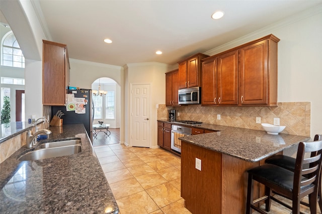 kitchen featuring a breakfast bar area, appliances with stainless steel finishes, sink, kitchen peninsula, and light tile patterned flooring