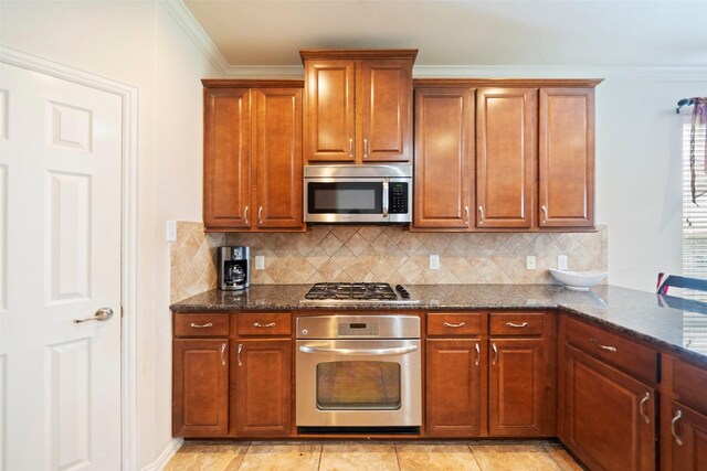 kitchen featuring light tile patterned flooring, tasteful backsplash, stainless steel appliances, and dark stone countertops