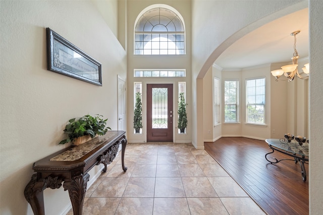 foyer featuring light hardwood / wood-style floors, a high ceiling, ornamental molding, and a chandelier