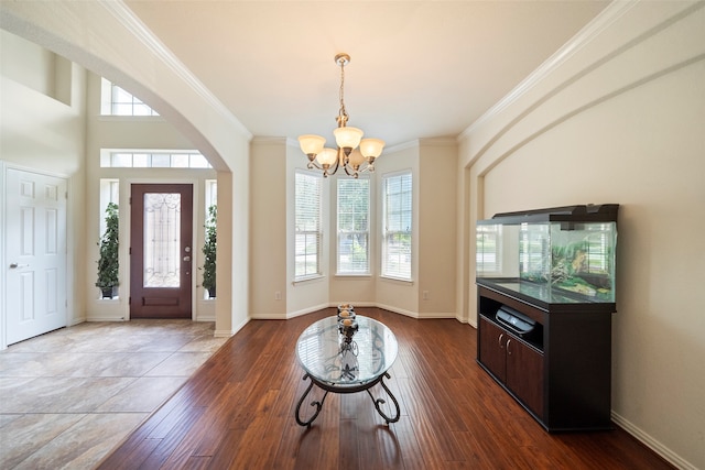 foyer entrance featuring wood-type flooring, ornamental molding, and an inviting chandelier