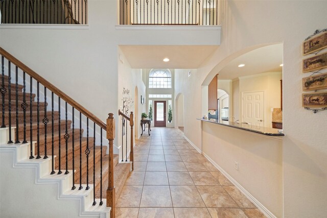 foyer entrance with light tile patterned flooring, a high ceiling, and ornamental molding