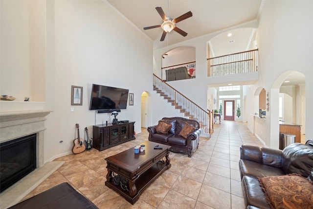 living room featuring ceiling fan, a high end fireplace, a high ceiling, and light tile patterned floors