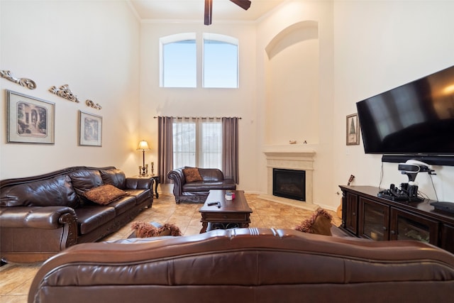 living room with a high ceiling, ceiling fan, light tile patterned floors, and ornamental molding