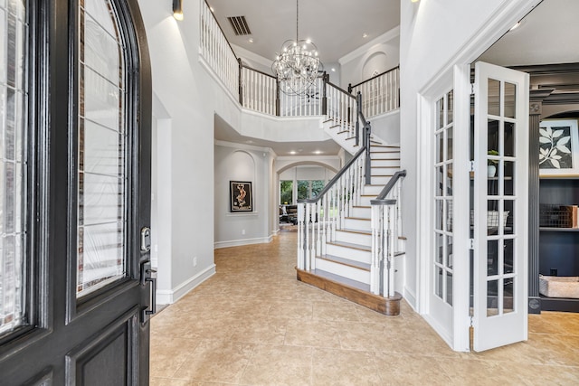 entryway featuring light tile patterned flooring, a towering ceiling, an inviting chandelier, french doors, and ornamental molding