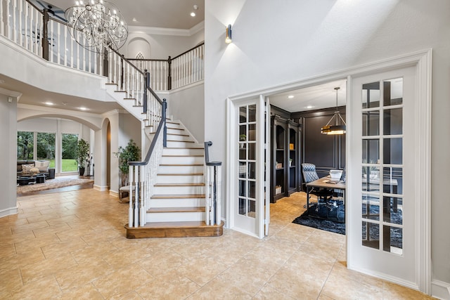 entrance foyer with ornamental molding, a high ceiling, and a chandelier