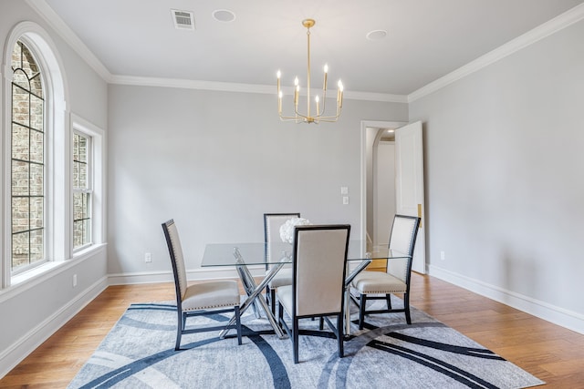 dining room featuring crown molding, an inviting chandelier, and light hardwood / wood-style flooring