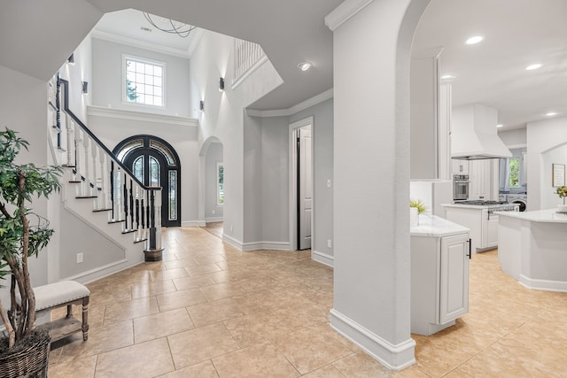 tiled foyer featuring plenty of natural light and crown molding