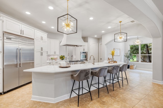 kitchen with appliances with stainless steel finishes, white cabinetry, a spacious island, and decorative light fixtures