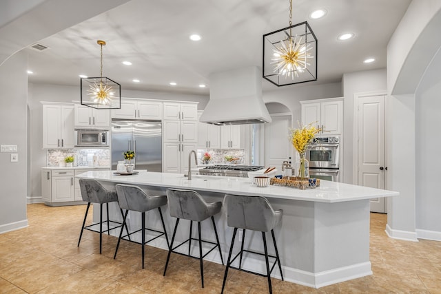 kitchen with a large island, a breakfast bar, custom range hood, and built in appliances