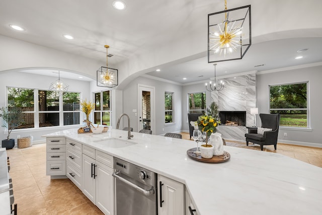 kitchen featuring hanging light fixtures, a fireplace, white cabinetry, and sink