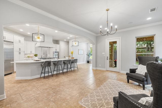 tiled living room with ornamental molding and a chandelier