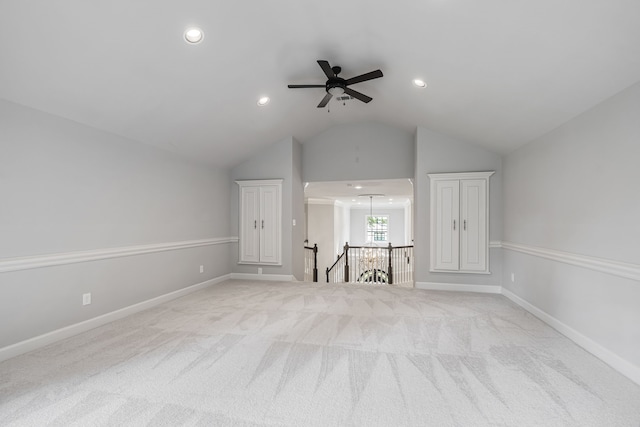 unfurnished living room featuring lofted ceiling, ceiling fan, and light colored carpet