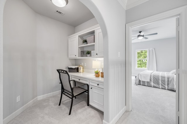 carpeted home office with built in desk and ceiling fan