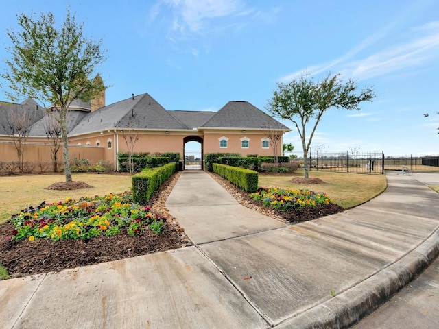 view of front facade with a front yard, fence, and stucco siding