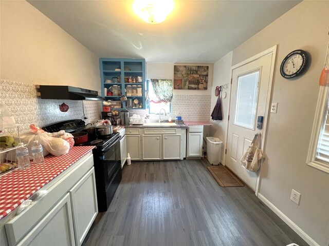 kitchen with black range with electric stovetop, wall chimney range hood, backsplash, dark wood-type flooring, and sink