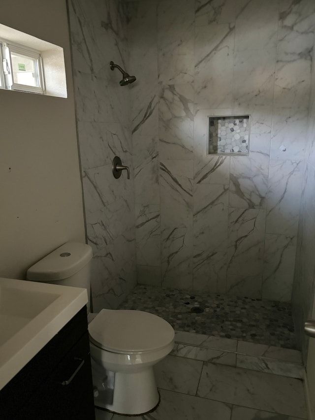 bathroom featuring tile patterned floors, a tile shower, vanity, and toilet