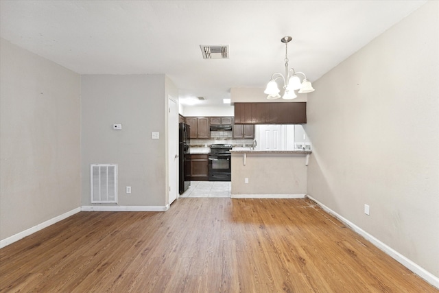 kitchen featuring light wood-type flooring, range with electric stovetop, a chandelier, and dark brown cabinets