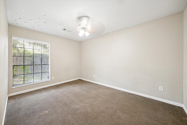 carpeted empty room with a wealth of natural light and ceiling fan