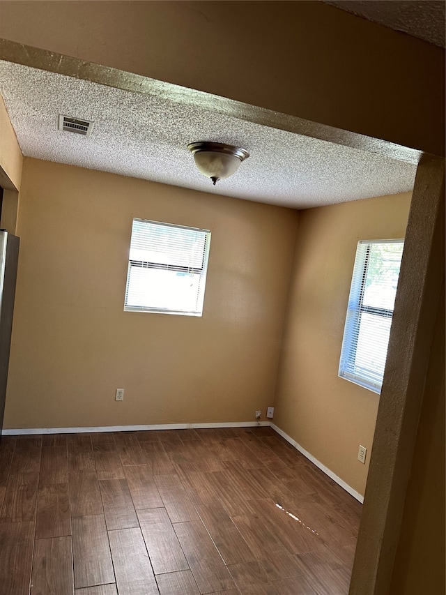 spare room with a textured ceiling and hardwood / wood-style floors