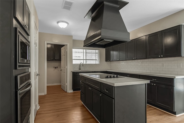 kitchen with light hardwood / wood-style flooring, backsplash, premium range hood, a center island, and stainless steel appliances