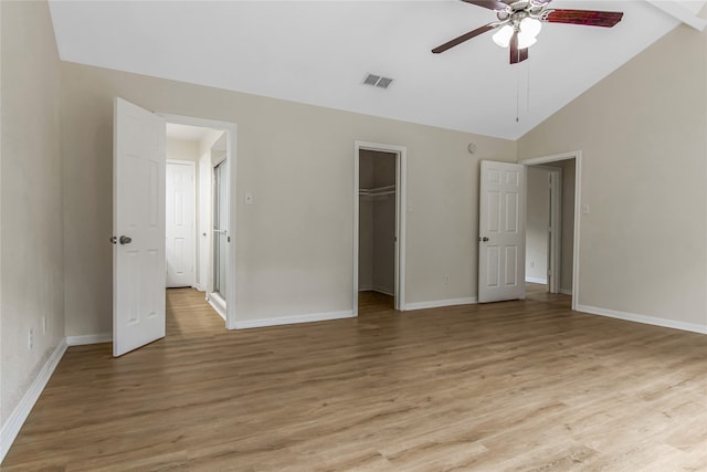 unfurnished bedroom with light wood-type flooring, visible vents, vaulted ceiling, and baseboards